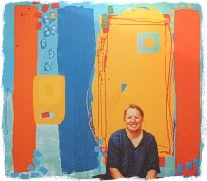 Sandy sitting in front of one of her paintings